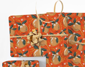 May include: Gift-wrapped presents with a repeating pattern of stylized oranges, green leaves, and white flowers on a red background. The gifts are tied with gold ribbon and bows, with a spool of ribbon nearby.