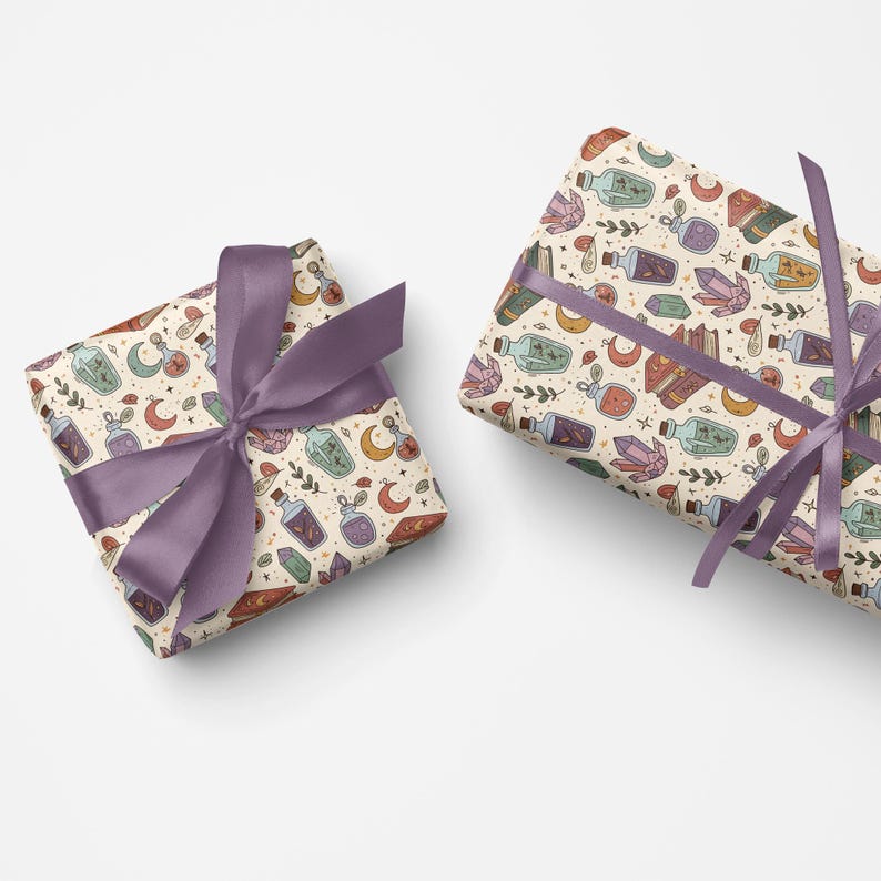 Puede incluir: Dos regalos envueltos con papel crema con un patr&oacute;n repetido de botellas de pociones, cristales, lunas y estrellas. Los regalos est&aacute;n atados con una cinta lavanda. El tema general es m&iacute;stico y m&aacute;gico.