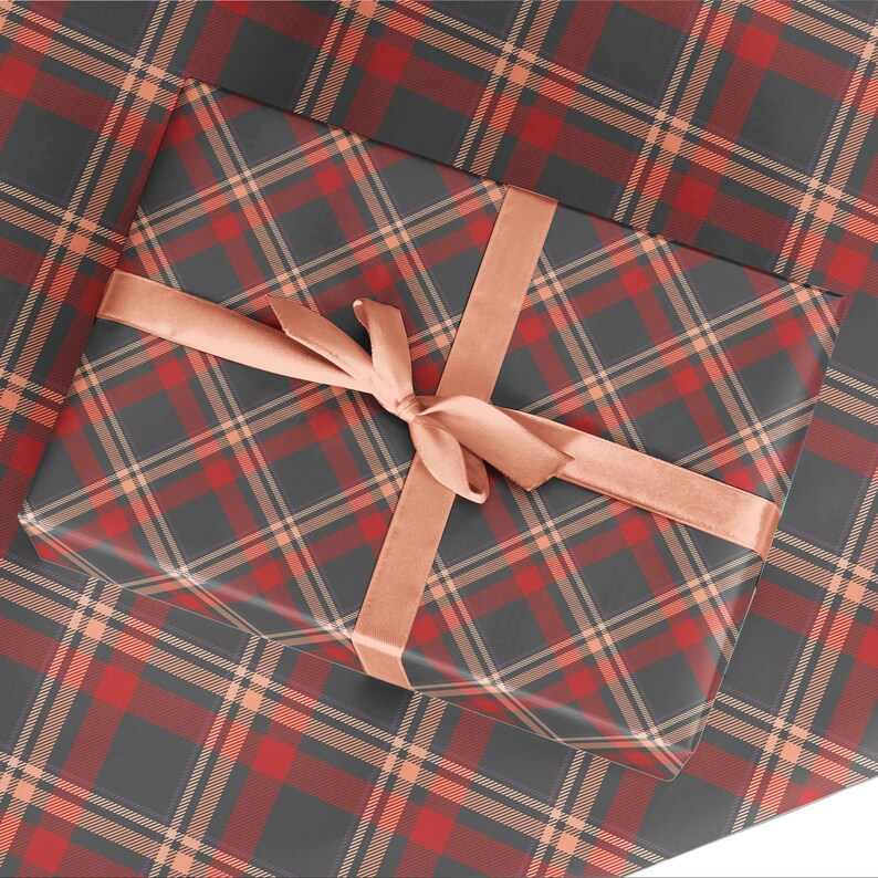 K&ouml;nnte beinhalten: Eine Geschenkbox, verpackt in rot-schwarzem kariertem Geschenkpapier mit einem pfirsichfarbenen Band, das zu einer Schleife gebunden ist.
