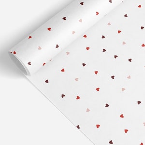 May include: White wrapping paper with a repeating pattern of small red, pink, and maroon hearts.