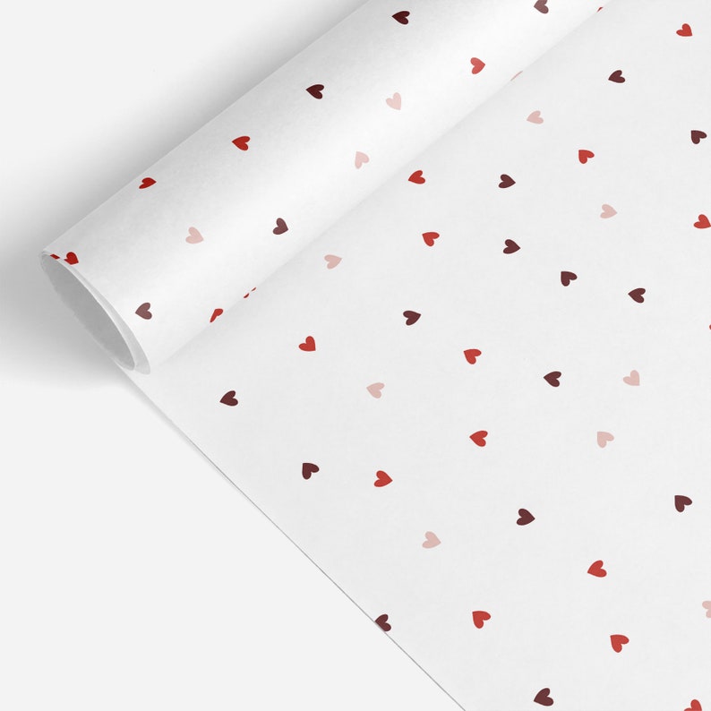 May include: White wrapping paper with a repeating pattern of small red, pink, and maroon hearts.