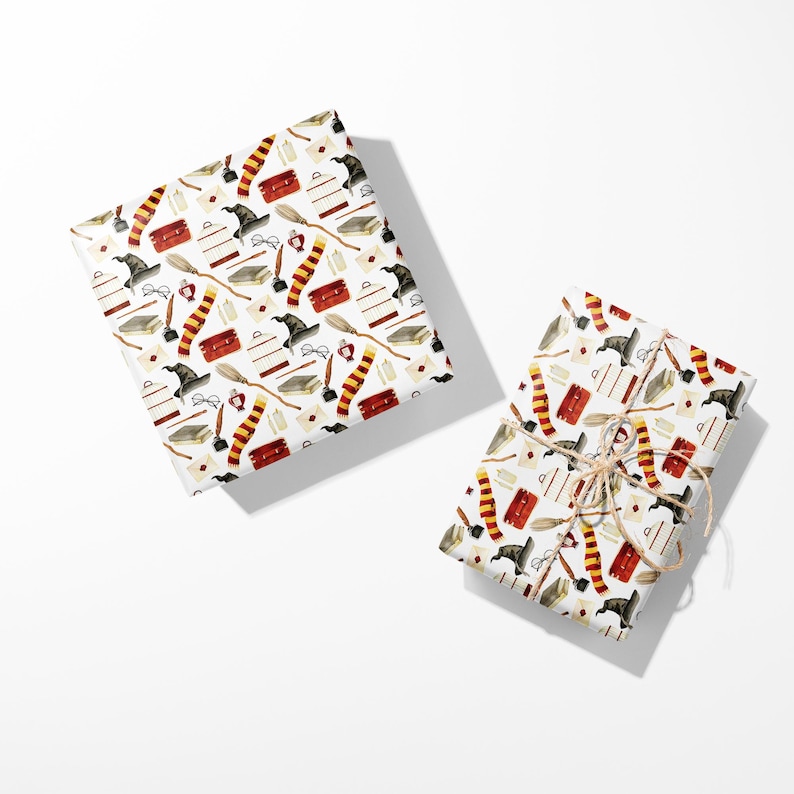 May include: Two wrapped gifts with a white background. The wrapping paper features a repeating pattern of black wizard hats, red and gold striped scarves, books, brooms, and other magical items.