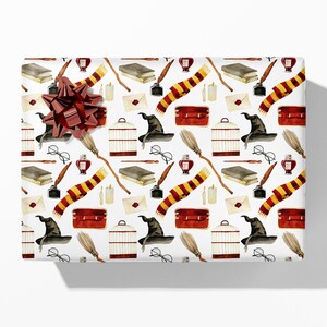 May include: White gift wrap featuring a repeating pattern of wizarding school-themed illustrations. The design includes books, scarves, quills, eyeglasses, cages, and hats. A large, red bow adorns the top of the wrapped gift.