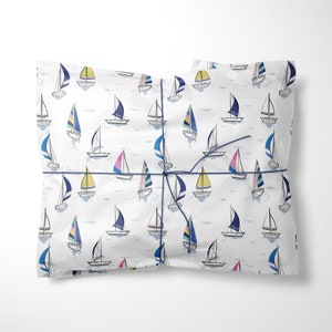 May include: White wrapping paper with a repeating pattern of colourful sailboats. The paper is tied with a blue ribbon.