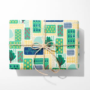 May include: A white gift wrap with a repeating pattern of green, yellow, blue, and red garden elements. The pattern includes trees, fences, flowers, and mushrooms. The gift wrap is tied with a brown twine bow.