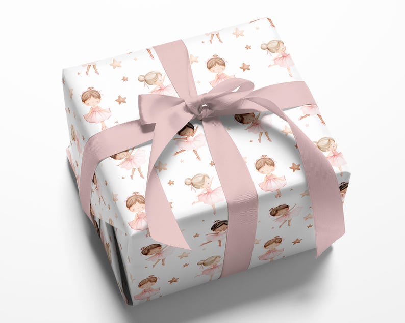 May include: A square gift box wrapped in white paper featuring a repeating pattern of watercolor illustrations of ballerinas in pink tutus and small gold stars, tied with a wide, smooth, light pink satin ribbon bow on the top surface.