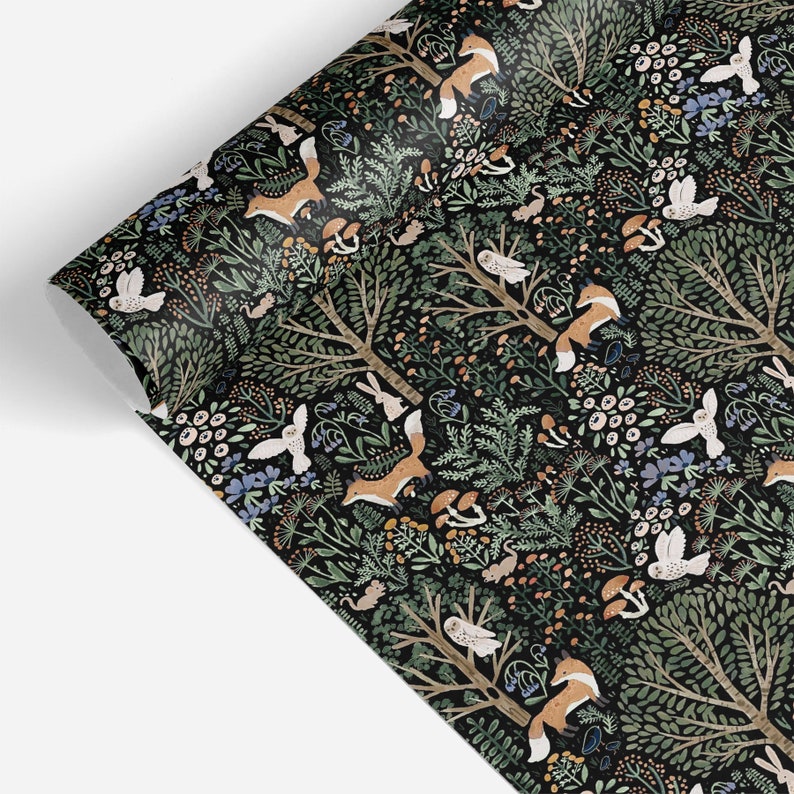 May include: A roll of wrapping paper featuring a dark black background with a repeating pattern of orange foxes, white owls, brown mushrooms, green trees, and various small woodland plants and flowers scattered throughout the forest scene.