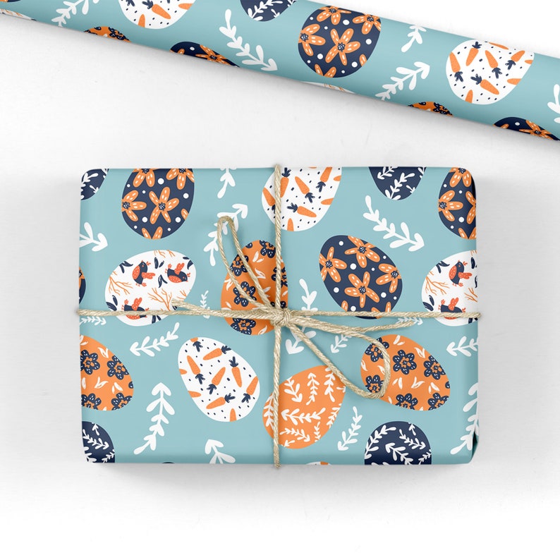 May include: A blue gift box wrapped in paper with a pattern of orange and blue Easter eggs. The box is tied with twine.