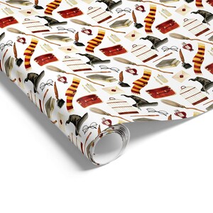 May include: White wrapping paper with a repeating pattern of wizarding school-themed illustrations. The design includes black wizard hats, red and gold striped scarves, eyeglasses, books, quills, and cages.