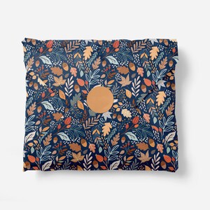 Puede incluir: Un sobre azul con una pegatina circular de papel marr&oacute;n. El sobre est&aacute; decorado con un patr&oacute;n de hojas, bellotas y bayas en tonos naranja, rojo y verde.