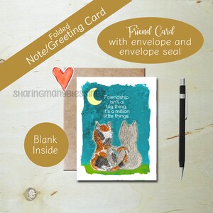May include: A folded greeting card with a blue background featuring two cats sitting back to back under a crescent moon. The card has the text "Friendship isn't a big thing. It's a million little things."