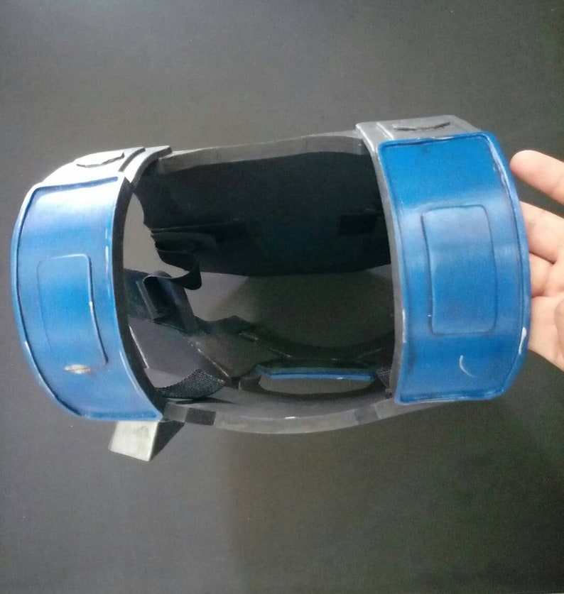 May include: A blue and gray plastic chest piece with straps. The chest piece has two blue panels with rectangular cutouts.