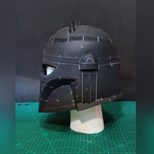Może przedstawiać: Czarny hełm z białymi oznaczeniami, zaprojektowany do cosplayu lub tworzenia rekwizyt&oacute;w. Hełm jest wykonany z pianki i ma fakturowaną powierzchnię.