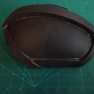 May include: A black foam piece with a curved shape and a raised edge. The foam piece has been painted black and has a smooth surface.