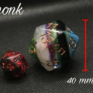 May include: Two polyhedral dice, one red and one with a multi-colored swirl pattern. The larger die is 40 mm in size and has the numbers 1, 3, 5, 7, 9, and 11 on its faces. The smaller die is red and has the numbers 4, 6, 8, 10, 12, and 16 on its faces.
