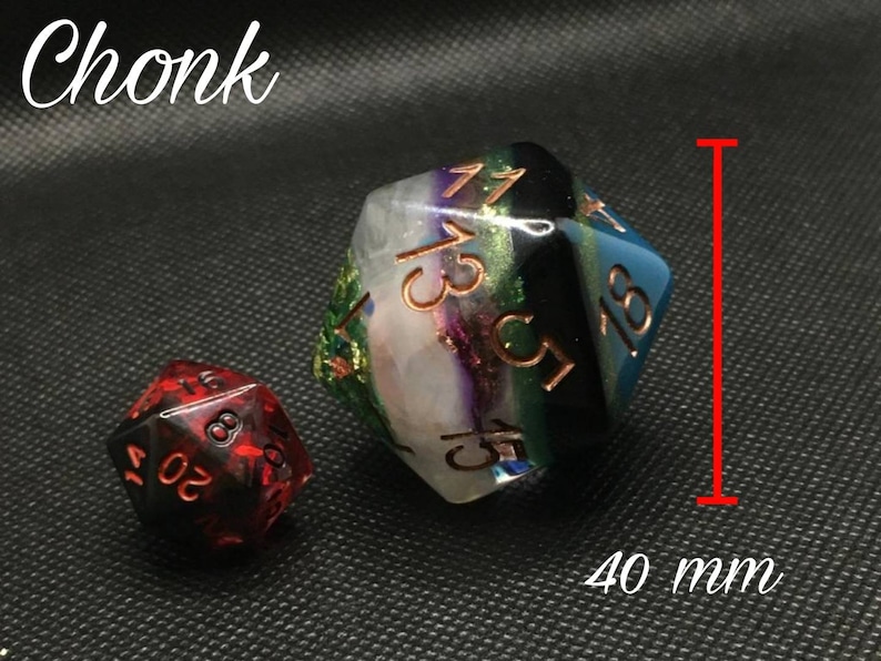 May include: Two polyhedral dice, one red and one with a multi-colored swirl pattern. The larger die is 40 mm in size and has the numbers 1, 3, 5, 7, 9, and 11 on its faces. The smaller die is red and has the numbers 4, 6, 8, 10, 12, and 16 on its faces.