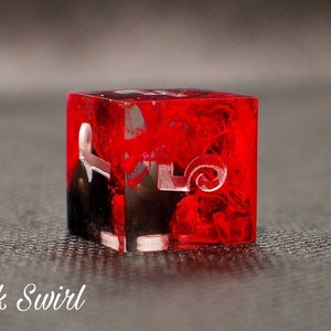 May include: A red and black dice with white ink swirl and numbers. The dice is made of clear resin and has a swirling pattern.