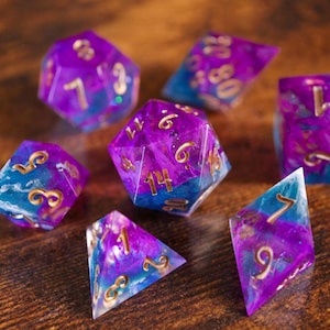 Puede incluir: Conjunto de siete dados poliédricos con un efecto de mármol azul y morado en espiral. Los dados tienen números dorados y son perfectos para juegos de rol de mesa.