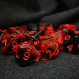May include: A group of red and black dice with white numbers. The dice are scattered on a black surface.