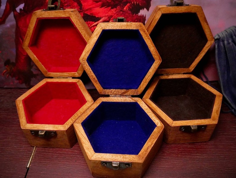 May include: Six wooden, hexagonal boxes with hinged lids are displayed open. The boxes have a natural wood finish and are lined with red, blue, and brown felt. Each box is approximately 10 cm wide.