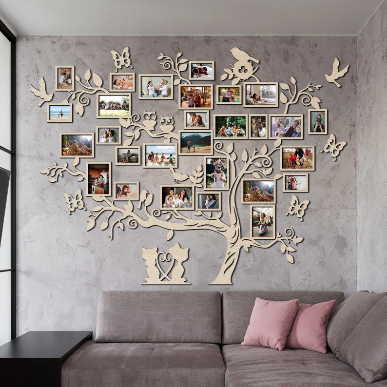 Puede incluir: Una decoraci&oacute;n de pared de madera con forma de &aacute;rbol con ramas y hojas. El &aacute;rbol est&aacute; decorado con m&uacute;ltiples marcos de fotos, cada uno con una imagen diferente. El &aacute;rbol tambi&eacute;n est&aacute; decorado con peque&ntilde;os recortes de madera de mariposas, p&aacute;jaros y b&uacute;hos. El &aacute;rbol est&aacute; montado en una pared gris, y hay un sof&aacute; gris en primer plano.