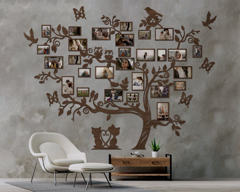 Puede incluir: Una decoraci&oacute;n de pared de &aacute;rbol geneal&oacute;gico de madera marr&oacute;n con m&uacute;ltiples marcos de fotos, que muestran im&aacute;genes de personas y animales. El &aacute;rbol est&aacute; decorado con p&aacute;jaros, mariposas y b&uacute;hos. El &aacute;rbol est&aacute; montado en una pared gris con una silla blanca y una mesa de madera delante.