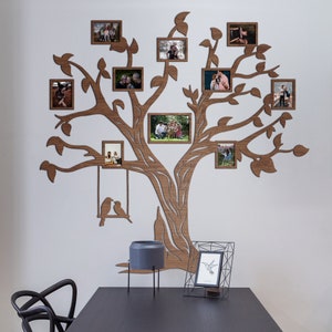 May include: A large brown wooden wall decal shaped like a tree with multiple branches and integrated rectangular photo frames. The design includes a decorative swing with two bird silhouettes and several empty spaces for displaying personal photographs.