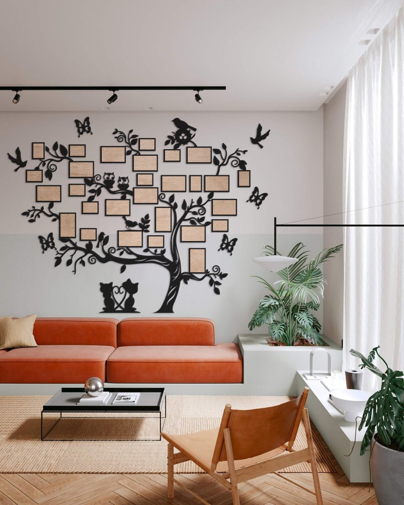 Puede incluir: Decoraci&oacute;n de pared de metal negro con un &aacute;rbol con ramas que sostienen m&uacute;ltiples marcos de fotos. El &aacute;rbol est&aacute; decorado con p&aacute;jaros, mariposas y un par de gatos. La decoraci&oacute;n est&aacute; montada en una pared blanca en un sal&oacute;n.