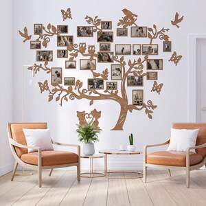 Puede incluir: Una decoraci&oacute;n de pared de madera con forma de &aacute;rbol con ramas y hojas. El &aacute;rbol tiene varios marcos de fotos unidos a &eacute;l, cada uno con una foto diferente. El &aacute;rbol est&aacute; montado en una pared blanca, y hay dos sillas de cuero marr&oacute;n delante de &eacute;l.