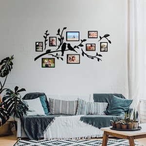May include: Black metal wall decor featuring a tree branch silhouette with two birds and multiple picture frames. The frames are empty and ready to be filled with photos.