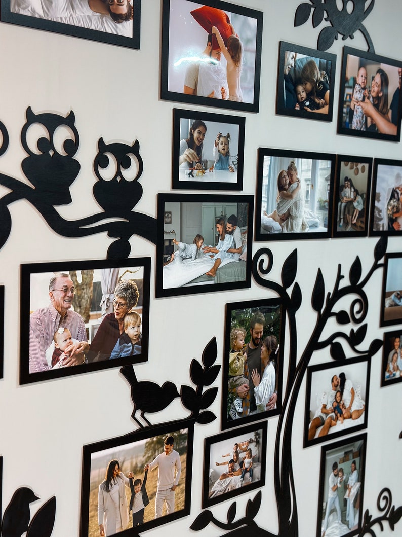 Puede incluir: Una silueta negra de un &aacute;rbol con ramas y hojas, con m&uacute;ltiples marcos de fotos negros colgados en una pared blanca. Los marcos contienen fotos de una familia, incluidos ni&ntilde;os, adultos y abuelos. La silueta del &aacute;rbol tiene dos b&uacute;hos y un p&aacute;jaro en las ramas.