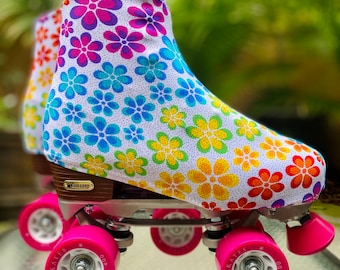 May include: A pair of roller skates with pink wheels and a white boot cover with a rainbow floral pattern. The boot cover has a white background with multi-colored flowers and white polka dots.