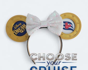May include: A Disney Cruise Line themed headband with gold-colored circular ears. The left ear features the "Disney Dream" logo, while the right ear has a Mickey Mouse emblem. A white sequined bow sits atop the headband, with the text "CHOOSE your CRUISE" below.