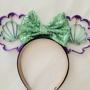 May include: Purple headband with a green sequin bow and two green seashell charms.