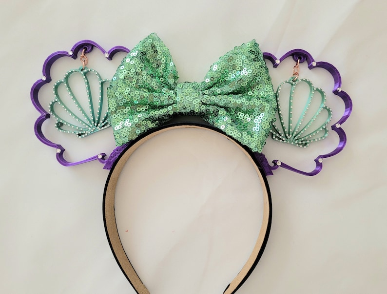 May include: Purple headband with a green sequin bow and two green seashell charms.