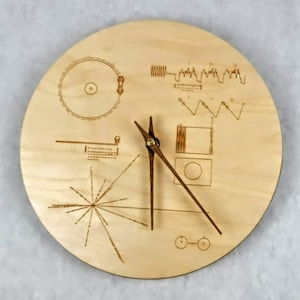 May include: A white ceramic mug with a black handle and the text "But First, Coffee" in a bold, black font. The mug is set against a blurred background, suggesting a cozy setting.