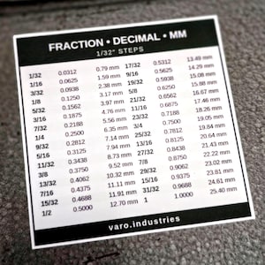 May include: A square white sticker with a black header reading FRACTION &bull; DECIMAL &bull; MM 1/32" STEPS. The sticker displays a conversion chart for fractions, decimals, and millimeters. The bottom of the sticker features the text varo.industries.