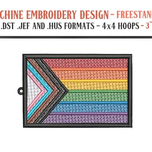 May include: Machine embroidery design featuring a Pride flag with a black border. The flag design includes a triangle with pink, white, light blue, and brown colors, and horizontal stripes in red, orange, yellow, green, blue, and purple. The text at the top reads "MACHINE EMBROIDERY DESIGN - FREESTANDING".