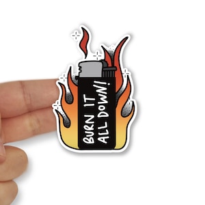 May include: A black and grey lighter with flames on either side. The lighter has the text "BURN IT ALL DOWN!" on it.