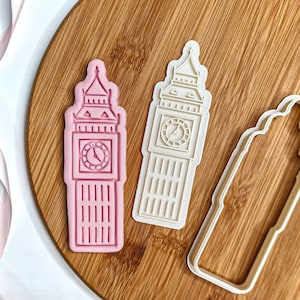 Könnte beinhalten: Drei Ausstecher in Form des Big Ben, dem berühmten Uhrturm in London. Die Ausstecher sind aus weißem Kunststoff und liegen auf einer Holzoberfläche.