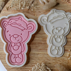 Könnte beinhalten: Zwei Ausstecher in Form von Teddybären mit Hüten. Der Ausstecher links ist rosa und der Ausstecher rechts ist weiß.