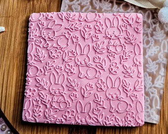 Op de afbeelding: Roze siliconen bakstempel met een herhalend patroon van konijnen en bladeren.