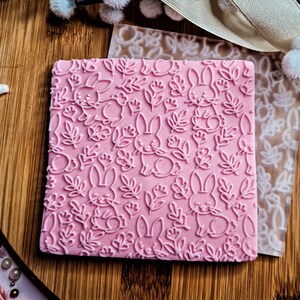 Peut inclure: Tampon en silicone rose avec un motif répété de lapins et de feuilles.