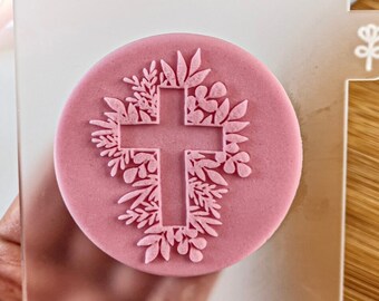 May include: A clear acrylic stamp with a pink silicone insert featuring a cross surrounded by floral designs.