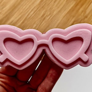 May include: Pink heart-shaped sunglasses mold for resin crafts. The mold is made of silicone and has a smooth, glossy finish.
