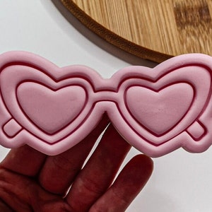 May include: Pink heart-shaped sunglasses cookie cutter.