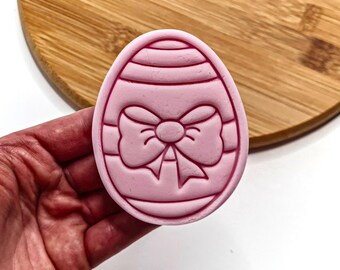 May include: Pink plastic Easter egg cookie cutter with a bow design.