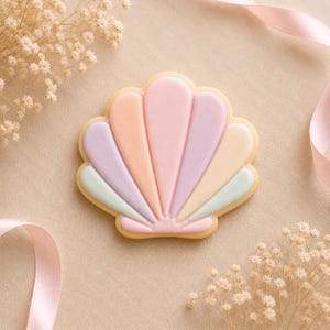 May include: A seashell-shaped biscuit decorated with smooth icing in pastel shades of pink, peach, lavender, and mint green. The biscuit features a fan-like design with distinct raised segments radiating from the centre base to the scalloped outer edge.