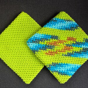 May include: Two square, knitted potholders. One is solid lime green. The other has a pattern of blue, teal, brown, and green horizontal stripes and a central design. The potholders are made of a textured yarn.