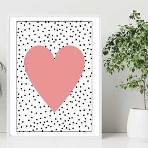 May include: A pink heart shape on a white background with black polka dots.